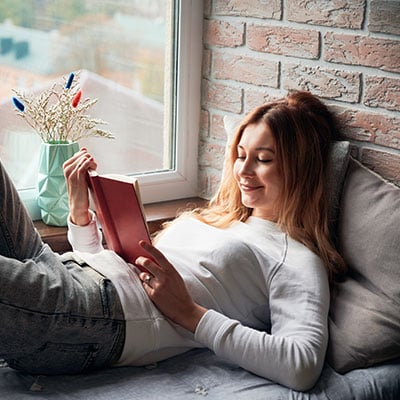 woman-is-lying-windowsill-bed-reading-book